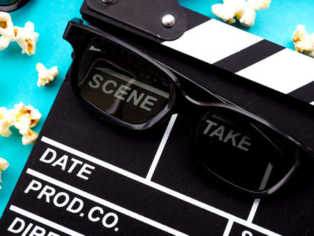 Popcorn and clapperboard on blue background. the concept of movie, film, entertainment, advertisingの写真素材