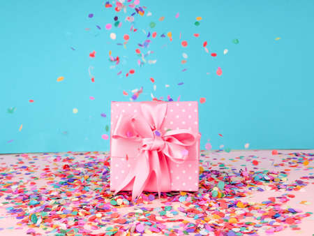 gift box and flying confetti, holiday atmosphere, on a blue and pink backgroundの写真素材