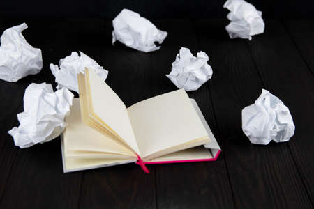 White note pad on a wooden table. Writing concept - crumpled up paper wads with Notepadの写真素材