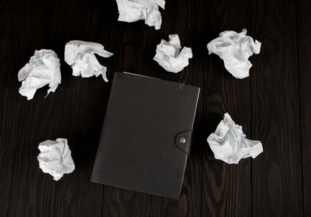 White note pad on a wooden table. Writing concept - crumpled up paper wads with Notepad