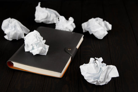 White note pad on a wooden table. Writing concept - crumpled up paper wads with Notepad