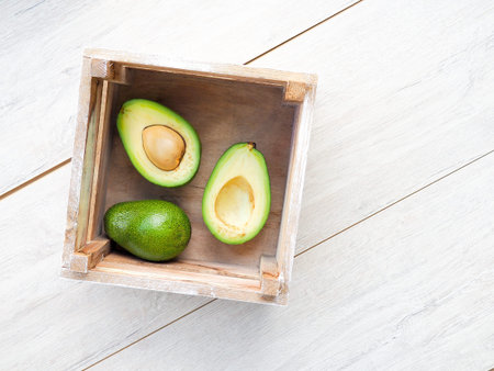 Avocado on old wooden table.Halfs on wooden bowl. Fruits healthy food concept. avocado in a wooden...