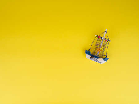 Vintage sailing boat ship on yellow. Wooden marine miniature, handmade souvenirs, minimalism is the concept of vacation.の写真素材
