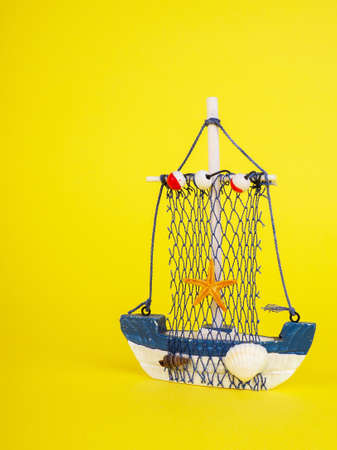 Vintage sailing boat ship on yellow. Wooden marine miniature, handmade souvenirs, minimalism is the concept of vacation.の写真素材