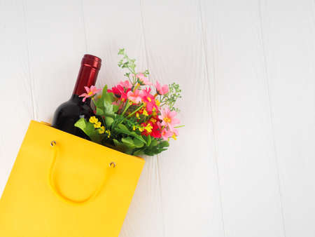 bottle of wine and flowers in the package on wooden background, space for text.の写真素材
