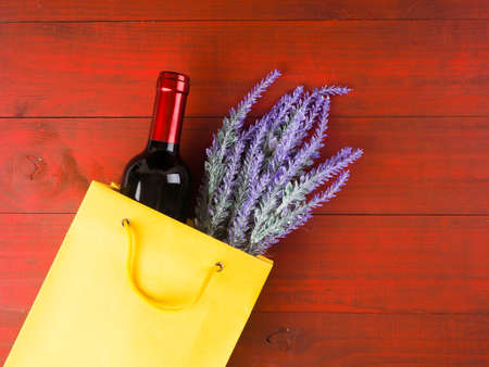 bottle of wine and flowers in the package on wooden background, space for text.の写真素材
