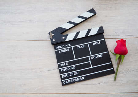 vintage classic clapperboard on brown wooden table whis red roses.の写真素材