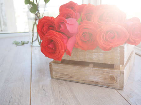 large bouquet of roses in a wooden box on a wooden background, for postcards, greetings, space for textの写真素材