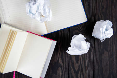 White note pad on a wooden table. near the notepads lies lot crumpled paperの写真素材