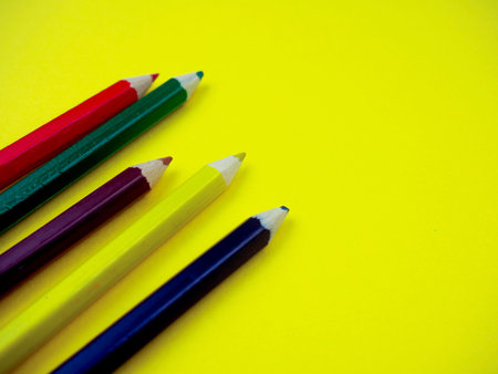 colored pencils on a yellow background, space for text.