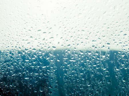 Water drop on the glass of windows background, raining on the glass off window city for backgroundの写真素材