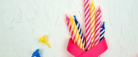 striped colorful candles with pink ribbon for birthday party on white background. flat lay.の写真素材