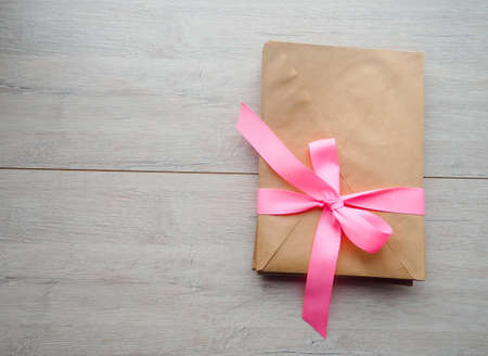 Gift kraft envelope with a ribbon on a wood background.の写真素材