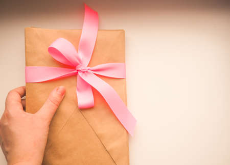 Gift kraft envelope with a ribbon on a wood background.の写真素材