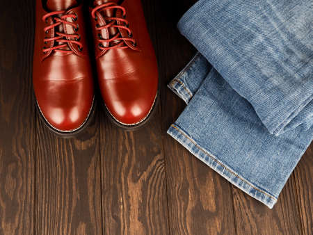 Fashionable concept. casual wear, yellow work boots from natural leather, blue jeans on black background. Trendy casual shoes clothes.の写真素材