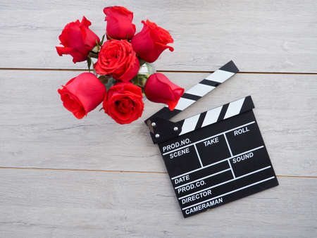 vintage classic clapperboard on brown wooden table whis red roses.の写真素材