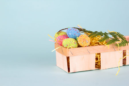 Easter eggs in egg cartoon box on blue background close up. Festive decorations. Happy Easter