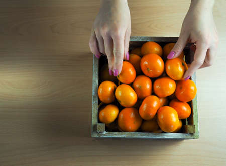 girl holding a box of tangerines, on a neutral background, space for textの写真素材