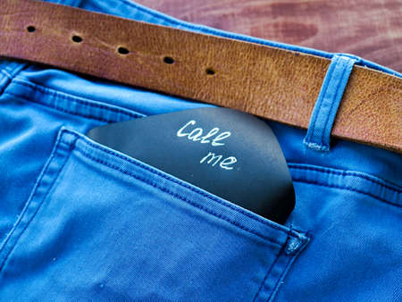 the phrase, a note, call me in the pocket of my jeans, standing on a wooden background, space for textの写真素材