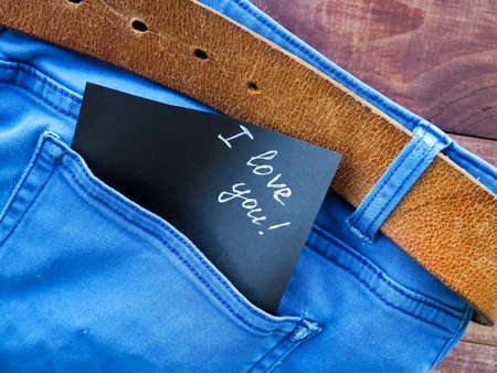 the phrase, a note I love you in the jeans pocket, on a wooden background, space for textの写真素材
