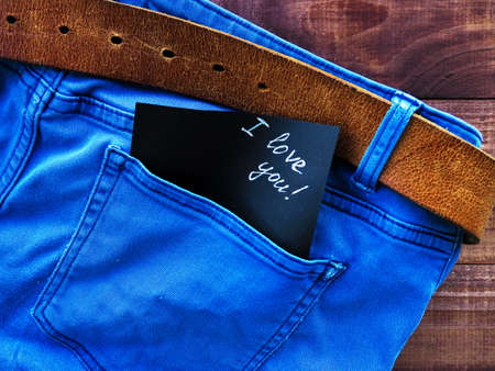 the phrase, a note I love you in the jeans pocket, on a wooden background, space for textの写真素材