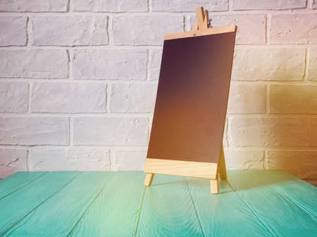 easel black against a brick wall, mockup empty space for design.の写真素材