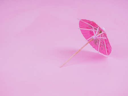 Cocktail umbrella. Pink paper cocktail umbrella isolated on pink.の写真素材