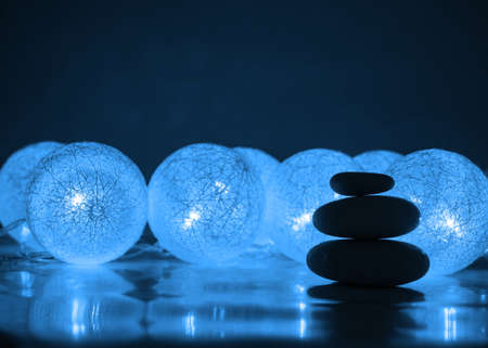 Stack of Zen stones on abstract dark background of Christmas garlands. Relax still Life with folded stones. Zen pebbles, stones, Spa-calm scenes to Christmas the soul of the imperturbable tranquility of the concept. copy space.の写真素材