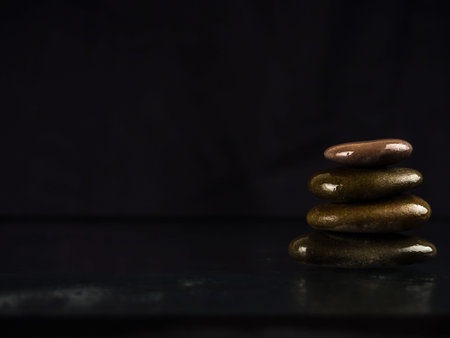 Spa Stones. black shiny zen stones with water drops over black background. Zen stones pile in...