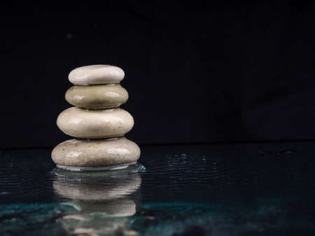 Spa Stones. black shiny zen stones with water drops over black background. Zen stones pile in raindrops, concept of calm, peace.の写真素材