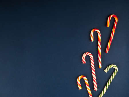 Christmas candy cane. On classic blue background. Flat lay. Christmas composition. A fan of caramel striped cane candies on a dark blue background. Minimalist New Year concept for your mockupの写真素材