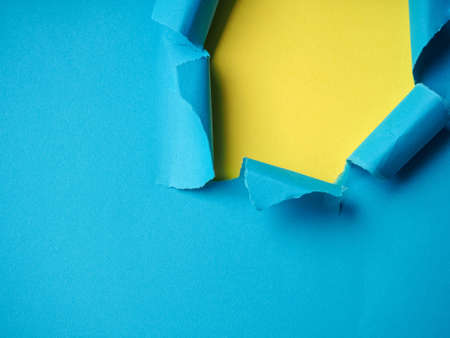 Ripped Paper Hole with blue and yellow colored background.の写真素材