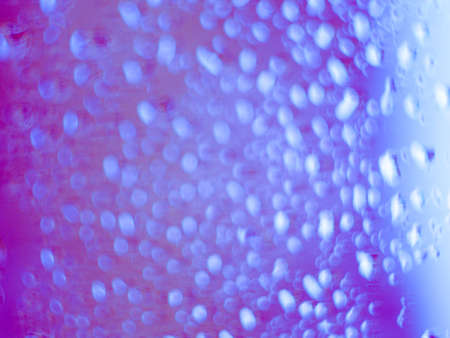 Close focus on water drop on colorful glass. Close focus on water drop on colorful window glass in blue and pink.の写真素材