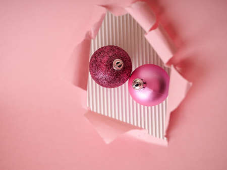 two pink Christmas balls in a torn paper hole, Christmas and new year concept.の写真素材