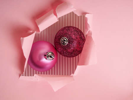 two pink Christmas balls in a torn paper hole, Christmas and new year concept.の写真素材