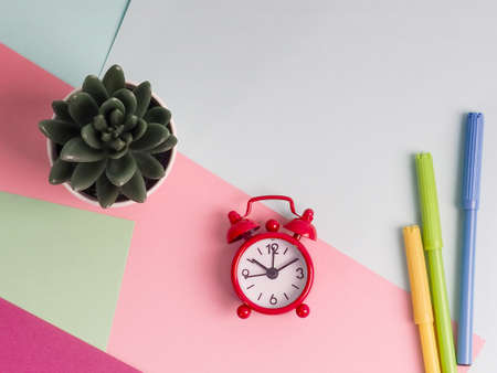 Alarm Clock, Note Pad, Pen and Potted Plant on Multi Colored Background.の写真素材