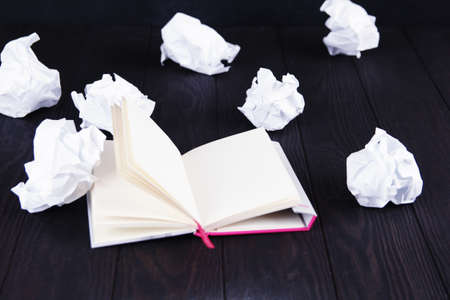 Writing concept - crumpled up paper wads with a sheet of white paper.の写真素材