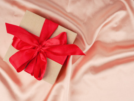 gift box with red bow, on a Nude satin background, wedding and Christmas concept.