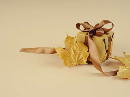 gift box with gold bow, on a gold satin background, wedding and autumn concept.の写真素材