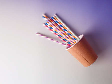 Kraft paper cup with colorful straws on blue background.の写真素材