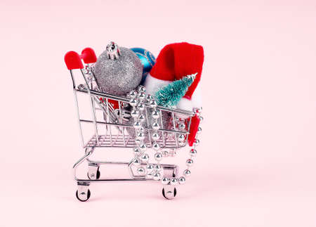 Shopping cart with gift or present and fir tree on snowy effect background. Christmas and New year sale concept. Vintage greeting cardの写真素材