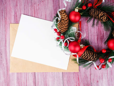 Christmas envelope with greetings design on red wooden background with Christmas wreath.の写真素材