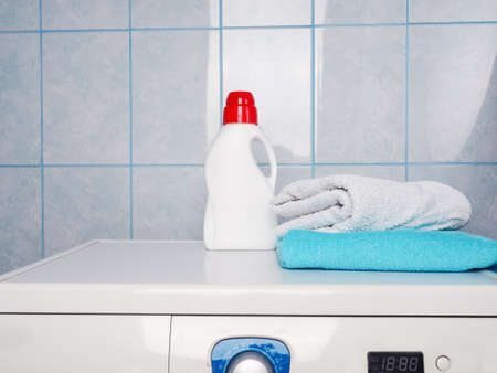 Bottle of detergent and clean towels on washing machine indoors, space for text. Laundry day.の写真素材