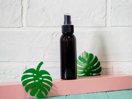 black bottle leaf monstera. Clean dropper bottle mockup and monstera leaf on white background.の写真素材