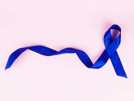 Blue ribbon on pink background, top view. Cancer awareness.の写真素材
