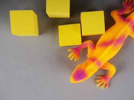 toy iguana lizard on a gray and yellow background, concept photo, space for textの写真素材