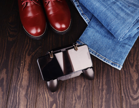 mens leisure concept, jeans, leather shoes, joystick on phone place for design