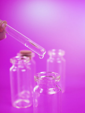 drop of liquid from a pipette into a medical bottle, research concept, new drugs and science, on a...