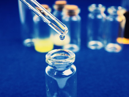 drop of liquid from a pipette into a medical bottle, research concept, new drugs and science, on a...