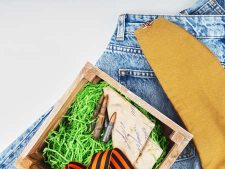 Wooden box inside symbols of mens day, Victory Day, ammunition, letters from the war, stands on modern jeansの写真素材